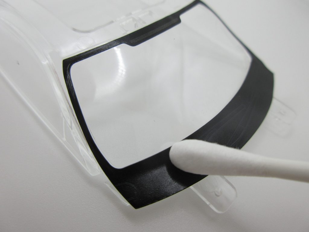 楽プラのシールを綿棒を使ってフロントガラスに密着させている画像。