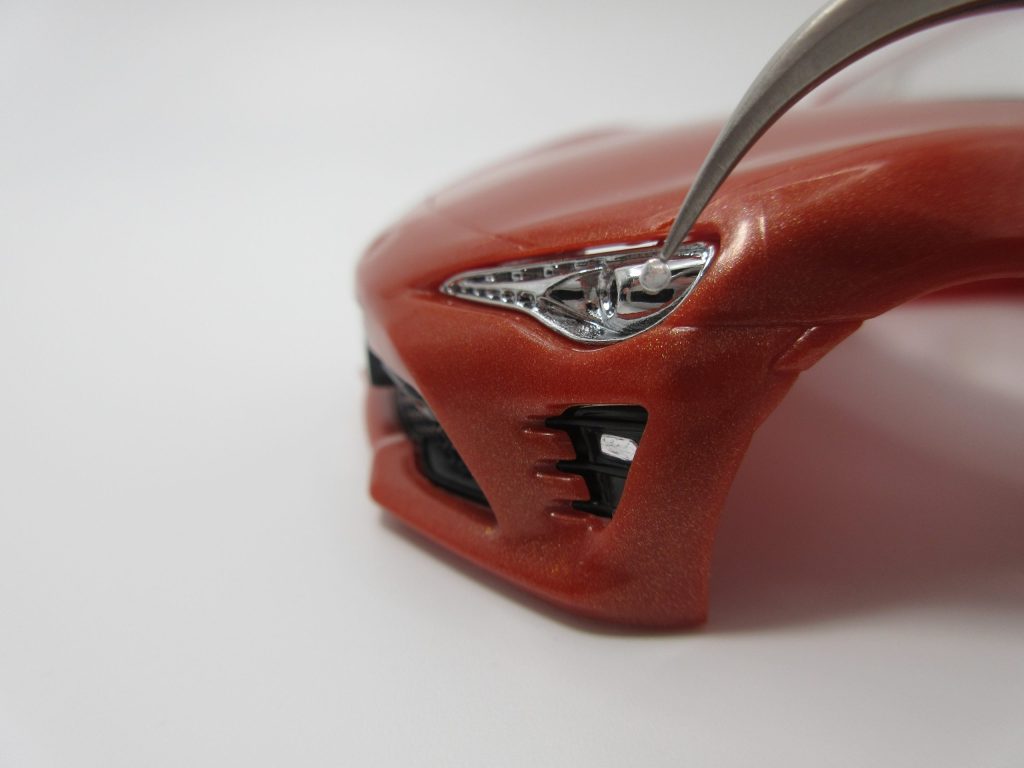 楽プラ８６のヘッドライトに極小シールをピンセットで貼り付けている画像