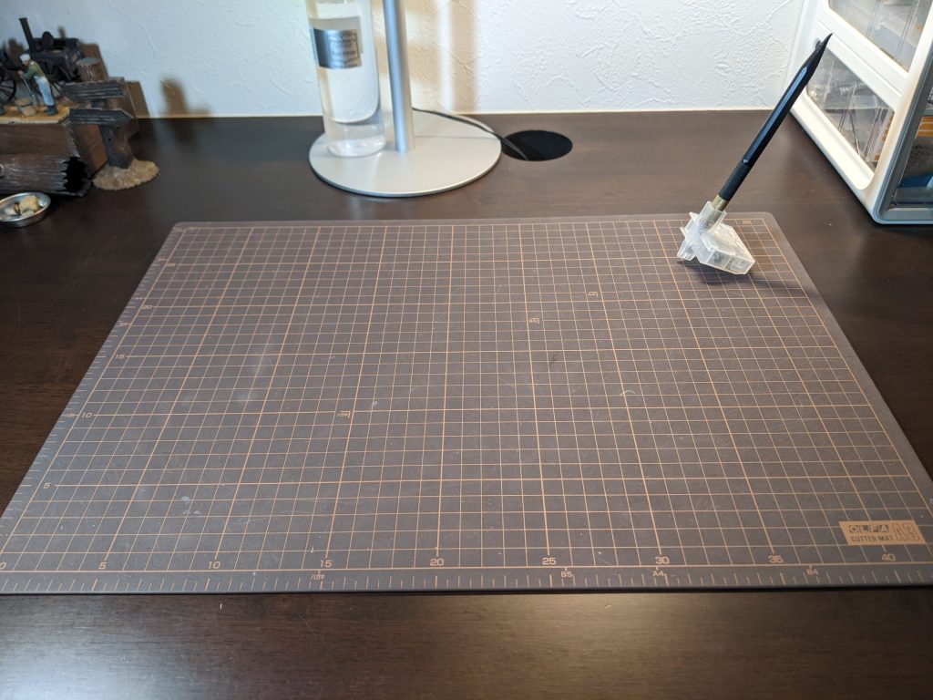 オルファカッターマットA3の裏面（ブラウン）を濃い木目の机に置いた画像